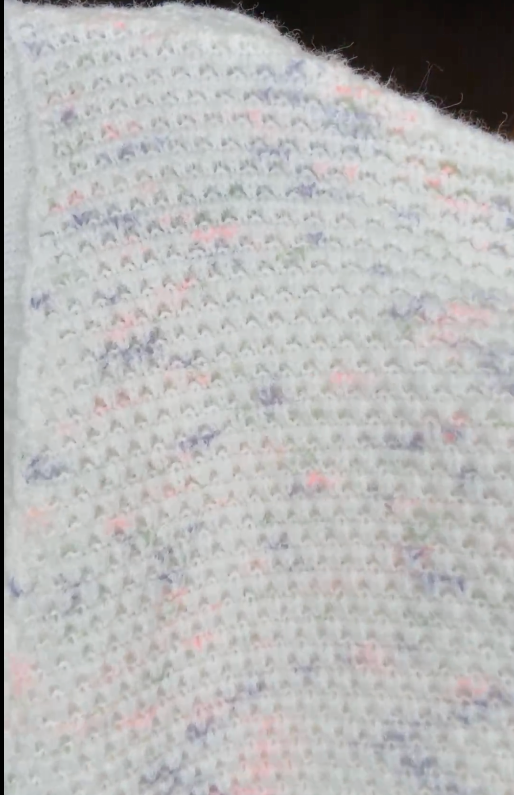 Pink Purple Green: Close-up of textured fabric with multicolor speckles on a dark background